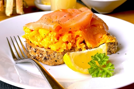 salmon and scrambled egg on toast with a slice of lemon